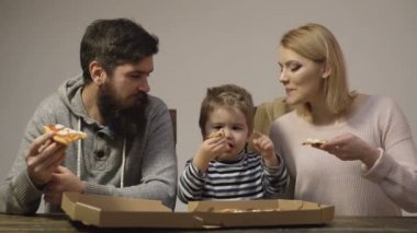 Aile lezzetli pizza sahiptir. Lezzetli pizza. Anne, baba ve oğul beyaz arka plan üzerinde birlikte pizza yiyor. Mutlu aile kavramı. Evde pizza paylaşımı mutlu bir aile portresi. Beslenme kavramı.