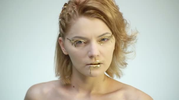 High Fashion Körperkunst. Frau mit goldener Haut und goldenen Lippen. Glamour glänzendes professionelles Make-up. Goldfarbe tröpfelt von Gesicht und Lippen der Frau. goldene Flüssigkeitstropfen auf Mädchenmund. — Stockvideo