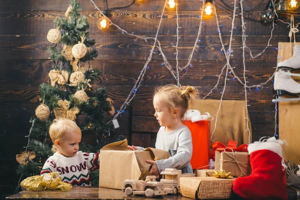 Niedliches kleines Mädchen schmückt den Weihnachtsbaum drinnen. Weihnachtskinder. Porträt eines glücklichen Kindes beim Anblick einer dekorativen Spielzeugkugel am Weihnachtsbaum. — Stockfoto