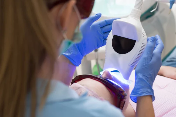 Młoda blond suczka otwarcie jej usta, gdy niezidentyfikowana dentysta w Rękawice lateksowe sprawdzać stan jej zęby. Close-up portret pacjentki u dentysty w klinice. — Zdjęcie stockowe