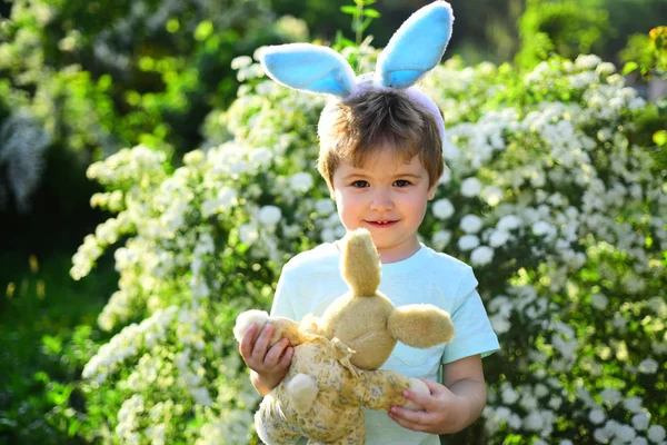 Konijn kind met bunny oren. Haas speelgoed. Kindje jongen in het groene woud. Egg hunt op voorjaar vakantie. hou van Pasen. Vakantie met het gezin. Vrolijk Pasen. Jeugd. Voorbereiding naar Pasen — Stockfoto