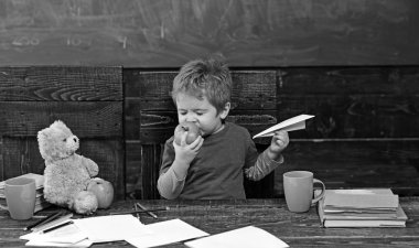 Çocuk yeme elma zevk ile. Sevimli çocuk meyve gözleri ile ısırma kapalı. Kağıt uçak ile oynayan bebek