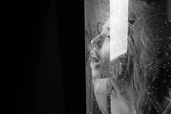 Shower and hygiene spa treatment. Window with water drops before girl with makeup. Sexy woman behind plastic sheet with water drops. Fashion and beauty. Rain drops on window glass with face of girl — Stock Photo, Image