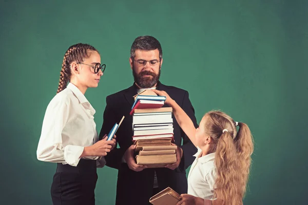 Teacher man and girls hold book pile at school. School time of sisters and father in library. Education in knowledge day. Literature lesson and reading grammar book. Back to school and home schooling — Stock Photo, Image