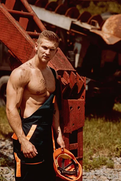 Concepto técnico. Técnico de confianza en maquinaria pesada. Técnico guapo en uniforme de trabajo. Técnico fuerte con brazos musculares y torso — Foto de Stock