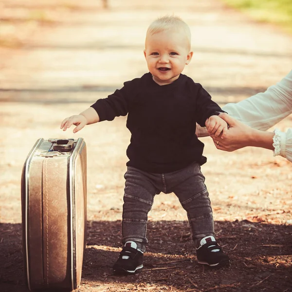 Niño llevar maleta en el paisaje natural. Viajes de niño de vacaciones con bolsa retro con la mano de las madres — Foto de Stock