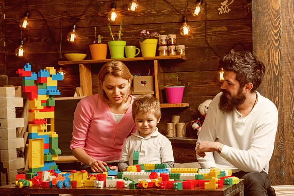 Concepto de construcción. Hijo pequeño con madre y padre juegan con bloques de construcción. Desarrollar habilidades sociales y generar confianza — Foto de Stock