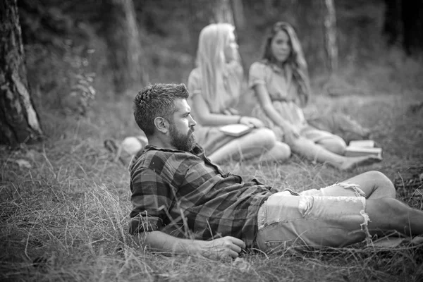 Homem bonito barbudo e duas meninas bonitas ou mulheres ao ar livre no dia ensolarado no fundo da floresta — Fotografia de Stock