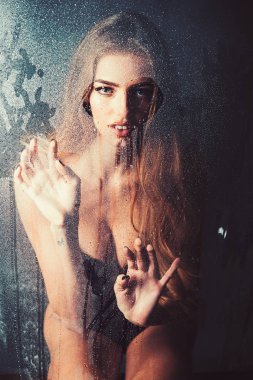 Kız makyaj ile daha önce su ile pencere bırakır. Duş ve hijyen kaplıca tedavisi. Kalp şeklinde pencere camına yağmur damlaları. Moda güzellik ve aşk. Damla su ile plastik levha arkasındaki seksi kadın