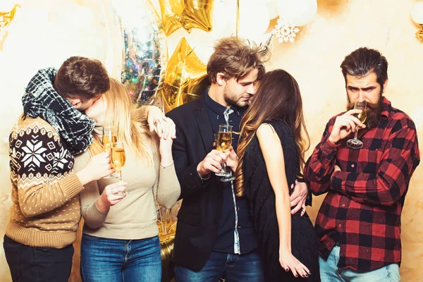 Femeile și bărbații se bucură de petrecere. Prietenii sărbătoresc Crăciunul sau Anul Nou. Bărbații și femeile beau șampanie. Cuplurile de îndrăgostiţi se sărută, relaţiile. Crăciunul și sărbătorile de Anul Nou — Fotografie, imagine de stoc