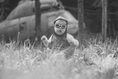 Çocuk pilot kask ve yeşil çim oturan gözlük