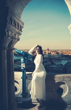 Teleskop üzerinde cityscape bakış açısı olan kadın. Şehvetli kadın beyaz gelinlik, moda uzun saçlı. Glamour bak ve makyaj, güzellik ile kız. Moda model seyahat tatil