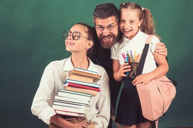 Akıllı gençler kütüphanede çalışıyoruz. Kız bir yığın kitap ve gülümseyen tutuyor.