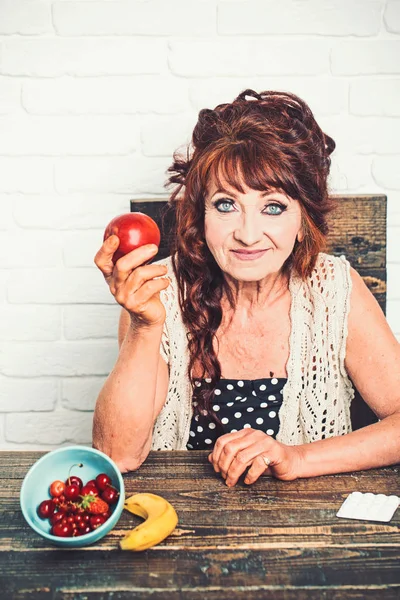 Mulher idosa sorri com maçã na mão — Fotografia de Stock