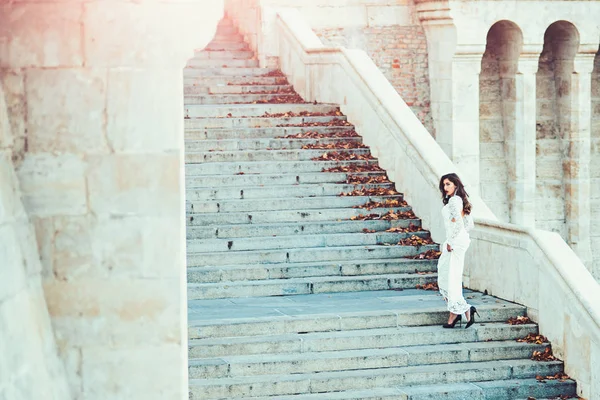 Femme mariée en robe de mariée blanche, mode. Femme sensuelle sur l'escalier. Fille au look glamour. Modèle de mode avec les cheveux longs sur les marches d'escalier. Architecture, structure et design — Photo
