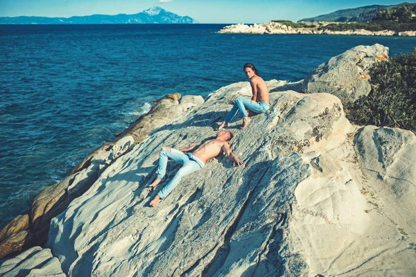 若い男と女が海に暖かい石の上に座って、どこかを. — ストック写真