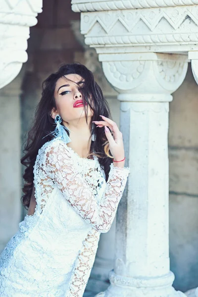 Braut mit Make-up Gesicht, Look. sinnliche Frau posiert an der Säule. Frau mit langen brünetten Haaren. Modemädchen in weißem Kleid. Beauty-Model mit Glamour-Make-up — Stockfoto