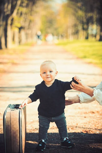 Kid traveler with luggage outdoor. Small boy carry retro suitcase on natural landscape. Child travel for vacation with bag with mothers hand. Vacation traveling and wanderlust — Stock Photo, Image