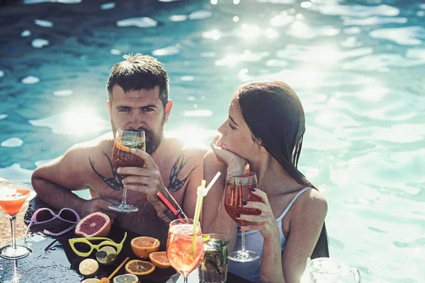 Paar bebaarde man en vrouw met cocktail en fruit in miami. Zomervakantie en zwemmen op zee. Cocktail in man en meisje op de Malediven. vrienden en familie. Zwembad partij relaxen in kuuroord — Stockfoto