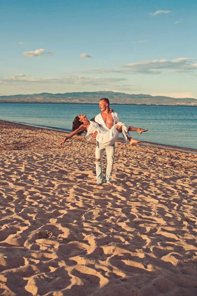 Concept de lune de miel. lune de miel de jeune beau couple avec l'homme tenant la femme sur les mains sur la plage de sable . — Photo