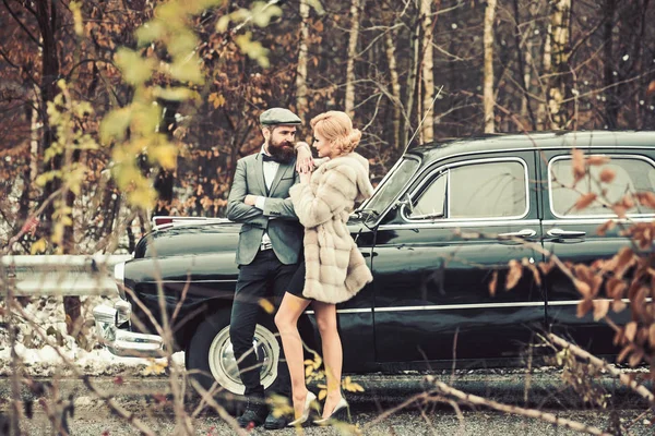 Escolta de rapariga pela segurança. Viagem e viagem de negócios ou engate caminhadas. Homem barbudo e mulher sexy em casaco de peles. Retro coleta de carro e reparação de automóveis por motorista mecânico. Casal apaixonado na data romântica . — Fotografia de Stock