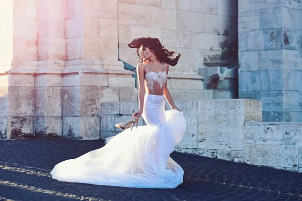 Bride girl at wedding ceremony in castle. Woman at stone ancient tower in summer. Sexy girl in white dress with stylish hair. Wedding fashion and beauty salon. Fashion model or princess in dress.