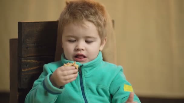 Närbild porträtt av en pojke som äter en pizza och håller tummen upp. Välsmakande pizza. Söt liten kaukasiska pojke äter pizza. Begreppet hälsosam mat. Hungriga barn tar en tugga från pizza. — Stockvideo