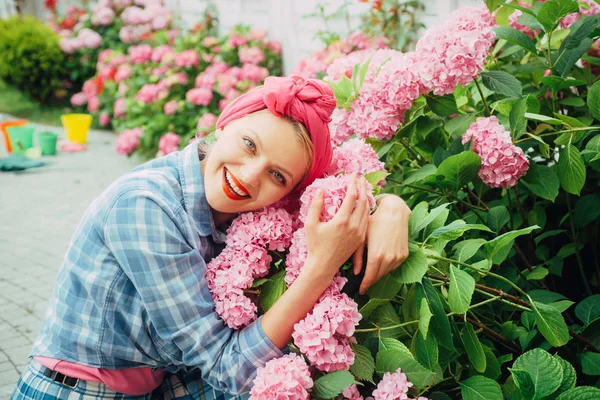 Ορτανσία. Την άνοιξη και το καλοκαίρι. Περιποίηση λουλουδιών και πότισμα. εδάφη και τα λιπάσματα. χαρούμενη γυναίκα κηπουρός με λουλούδια. γυναίκα φροντίδα των λουλουδιών στον κήπο. Λουλούδια του θερμοκηπίου. Καλώς ήρθατε στον κόσμο μας — Φωτογραφία Αρχείου