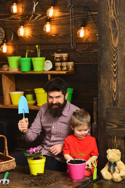 Father and son. happy gardeners with spring flowers. Flower care watering. Soil fertilizers. bearded man and little boy child love nature. Family day. Greenhouse. we love to work with flowers