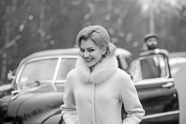 sexy woman in luxury fashion coat and man driver. sexy woman with stylish hair and makeup at driver in retro car.
