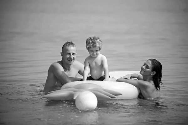 Καλοκαιρινές διακοπές και τα ταξίδια προς την ωκεανό. Φουσκωτά ανανά ή στρώμα αέρα. Μαλδίβες ή Μαϊάμι Μπιτς χαρά δραστηριότητα. Πατέρας και μητέρα με το γιο να παίξει μπάλα στο νερό. Ευτυχισμένη οικογένεια ζευγάρι στην Καραϊβική Θάλασσα — Φωτογραφία Αρχείου