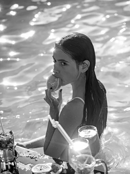Vacker kvinna i en baddräkt njuter cocktail i en pool. — Stockfoto
