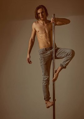 Genç güçlü kutup dans adam gri Studio pilon üzerinde.