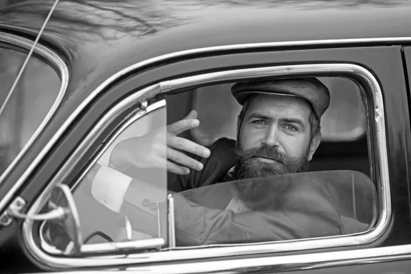 Retro man in retro car showing communicative gesture.