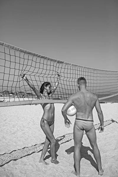 女と男がビーチでスポーツを行います。勝利と報酬の概念。スポーティなアクティブなカップルは、バレーボール ・夏の日にネット近くに立ちます。カップルは、楽しい時を過すビーチバレーを再生 — ストック写真