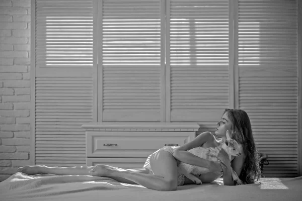 Mladá žena hýčkat malé jehně v posteli — Stock fotografie