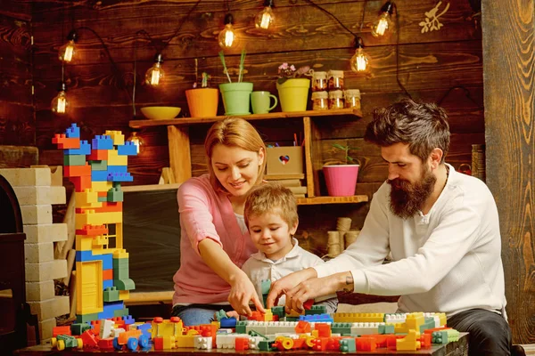 Concepto de construcción. Niño pequeño con madre y padre juegan con el juego de construcción de juguetes. Modelo de estructura de construcción familiar con juguetes de construcción. Construcción de casa de ensueño — Foto de Stock