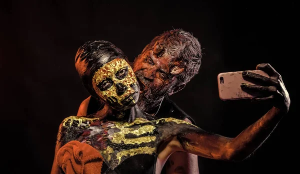 Halloween man satan and woman skeleton pose for smartphone — Stock Photo, Image