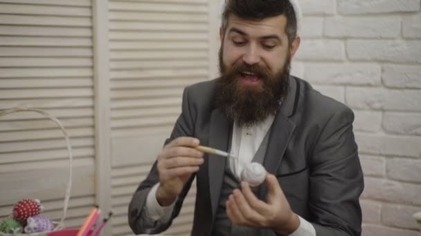 Sakallı adam Paskalya yumurtaları boyuyor. Paskalya için hazırlanıyor Bunny kulakları giyen funy hipster adam. Aile Paskalya için hazırlanıyor. Ahşap arka planda Paskalya yumurtaları. Bunny kulakları ile tavşan adam. — Stok video