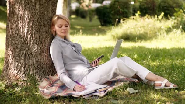 Escritório ambiente natural. Trabalho ao ar livre benefícios. Mulher com computador portátil trabalhar ao ar livre. Tecnologia da educação e conceito de internet. Trabalho da menina com laptop no parque sentar na grama . — Vídeo de Stock