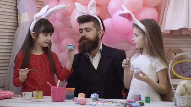 Far och två döttrar dekorera och måla påskägg. Lycklig familj förbereder sig för påsk. Söta små flickor som bär bunny öron på tröskeln till påsk helgen. Lycklig påsk familj. — Stockvideo