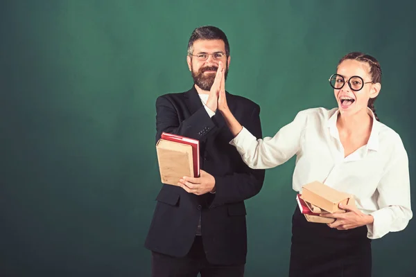 Dois alunos aplaudem as mãos em conjunto com bookd em fundo quadro-negro verde, espaço de cópia . — Fotografia de Stock