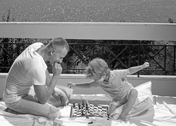 Kind spielt Schach mit Vater. Kind und Vater auf Balkon mit Meerblick. — Stockfoto