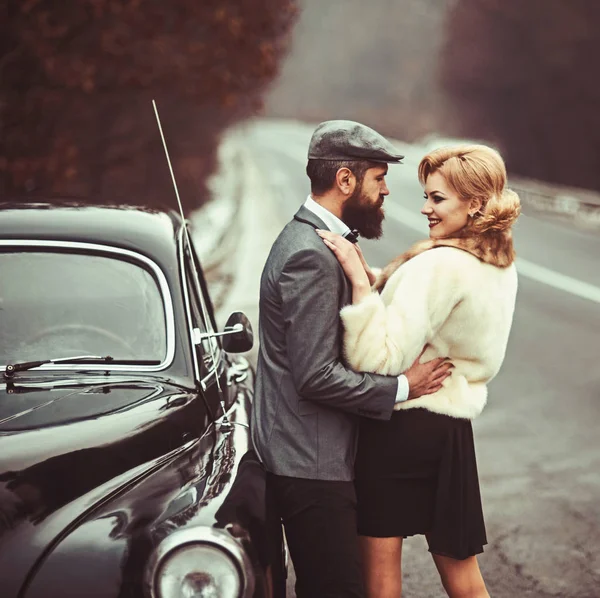 Casal apaixonado no encontro romântico. Viagem e viagem de negócios ou engate caminhadas. Homem barbudo e mulher sexy em casaco de peles. Retro coleta de carro e reparação de automóveis por motorista mecânico. Escolta de menina por segurança — Fotografia de Stock