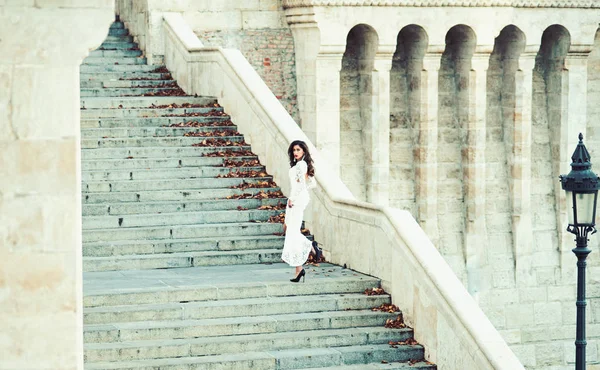 Noiva de moda em vestido de noiva branco na escada. Modelo de moda com cabelo longo em degraus escada, casamento — Fotografia de Stock
