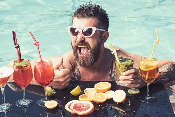 Ontspannen aan zee en spa resort. Man zwemmen en drinken alcohol. Zomervakantie in Miami of de Malediven. Zwembad partij, vitamine en dieet. Cocktail met fruit op de bebaarde man in zwembad. — Stockfoto