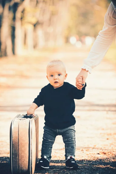 Outdoor portrait of funny little boy walking down road in countryside, holding old suitcase. — Stock Photo, Image