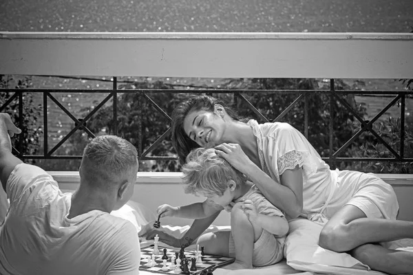 Summer vacation of happy family. Child play chess with father and mother. Family travel with kid on mothers or fathers day. Mother and father with son on balcony. Love and trust as family values. — Stock Photo, Image