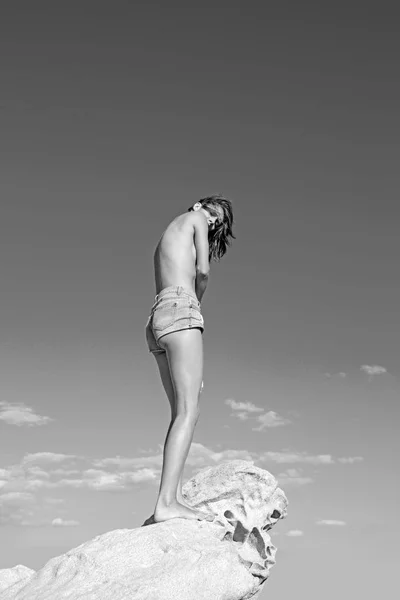 スタイリッシュな女性トップレス立って石の海岸で、海で探して. — ストック写真