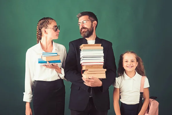 De vuelta a la escuela y a la educación en casa. Lección de literatura y lectura de libro de gramática. Tiempo escolar de hermanas y padre en la biblioteca. Jornada de educación en conocimiento. Maestro hombre y niñas celebrar libro pila en la escuela —  Fotos de Stock